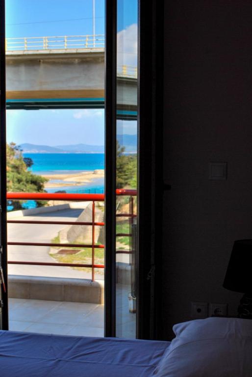 a bedroom with a window looking out at the ocean at Canal Luxury Apartments in Nea Potidaea