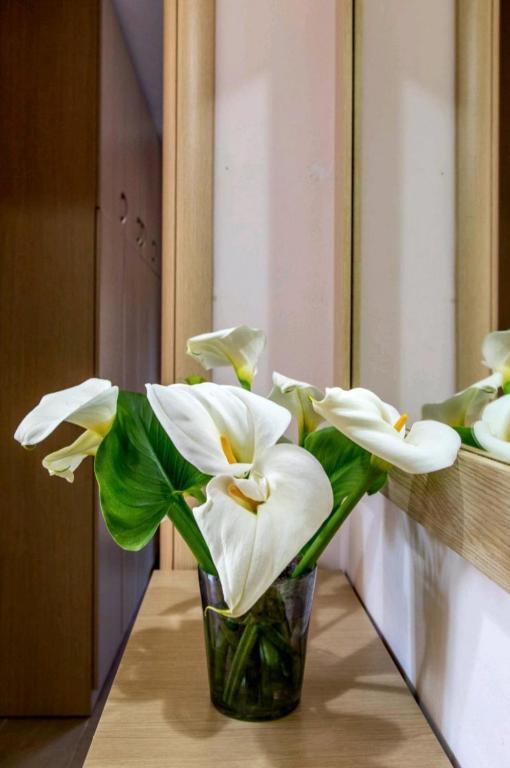 a vase filled with white flowers sitting on a table at Canal Luxury Apartments in Nea Potidaea