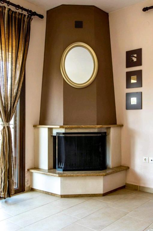a living room with a fireplace and a round mirror at Canal Luxury Apartments in Nea Potidaea