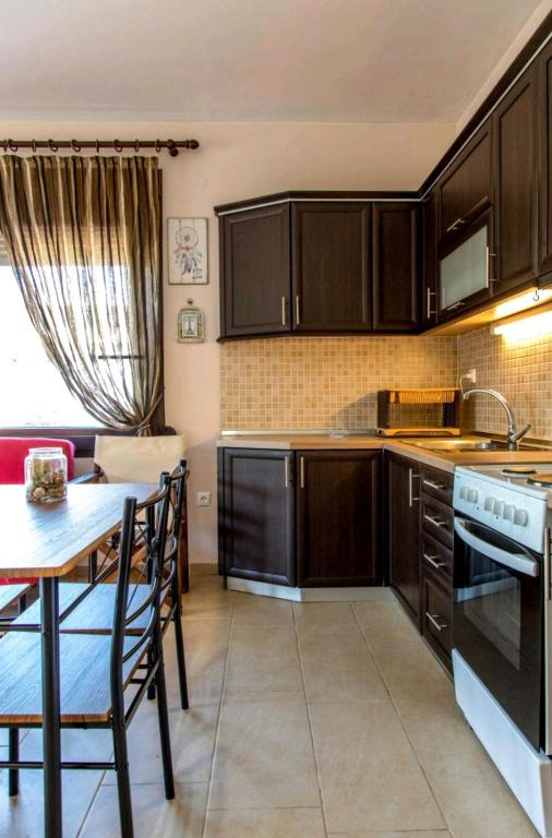 a kitchen with wooden cabinets and a table and a table and chairs at Canal Luxury Apartments in Nea Potidaea