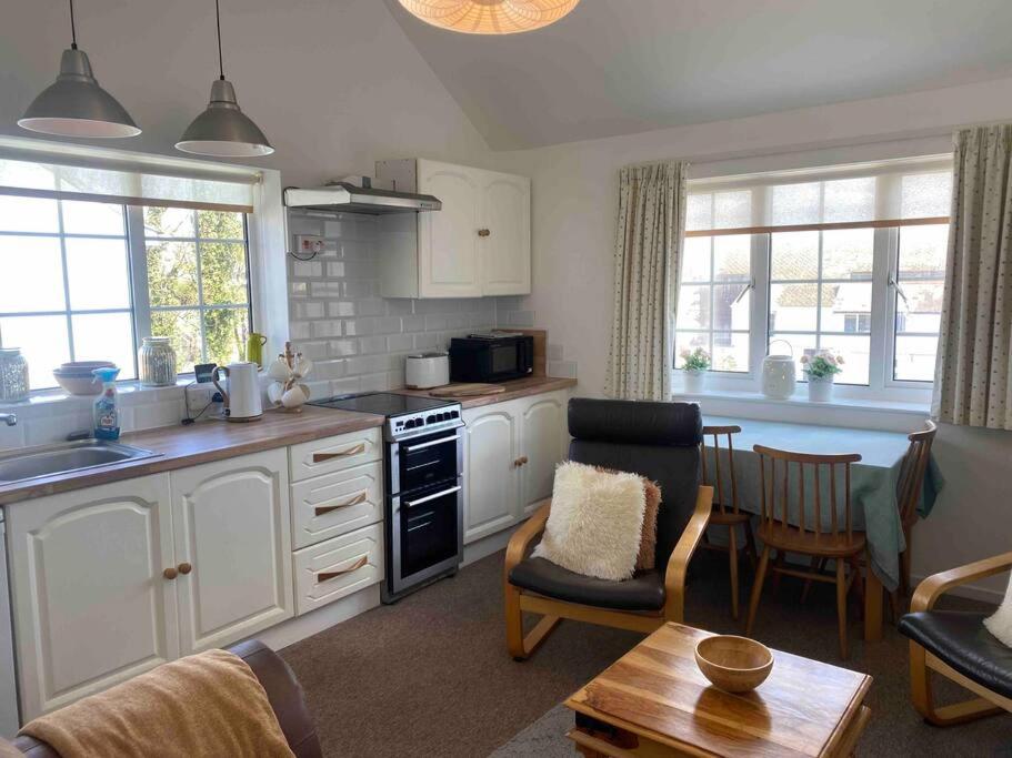 a kitchen with white cabinets and a living room at Large property which is all about location, location , location ! Lovely Comfortable 2 bedroom flat which is spacious and one of the best value properties of this size so close to the sea , beaches and restaurants 1 min to the sea ! in Lyme Regis