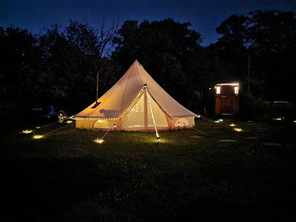 Tienda blanca con luces en un campo por la noche en Quex Livery Glamping, en Birchington