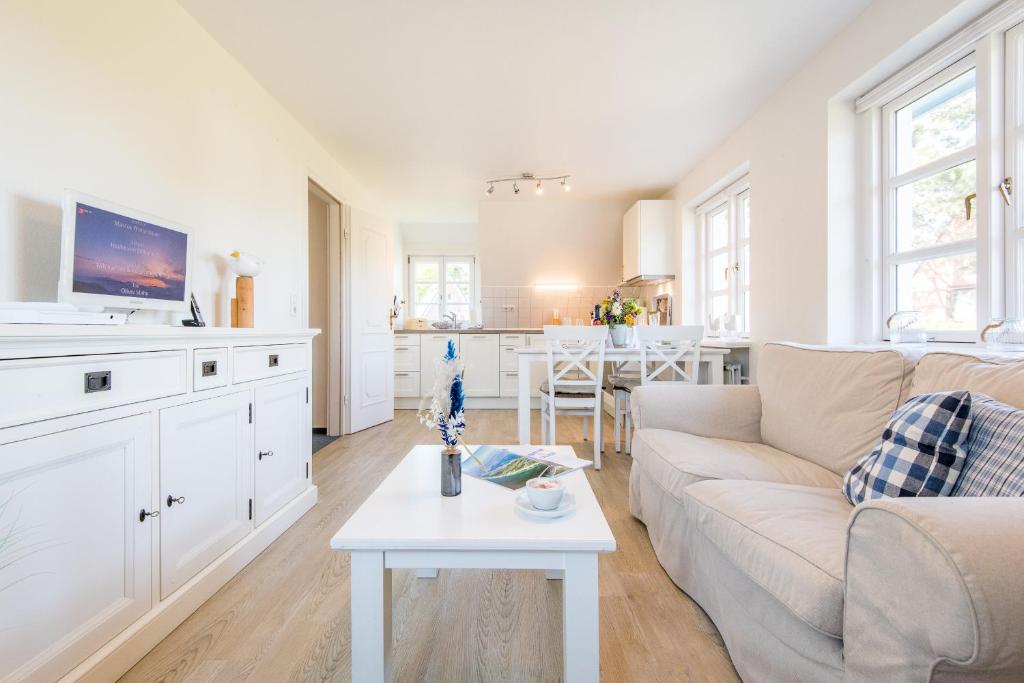 ein weißes Wohnzimmer mit einer Couch und einem Tisch in der Unterkunft Haderslebener Str 28 in Westerland
