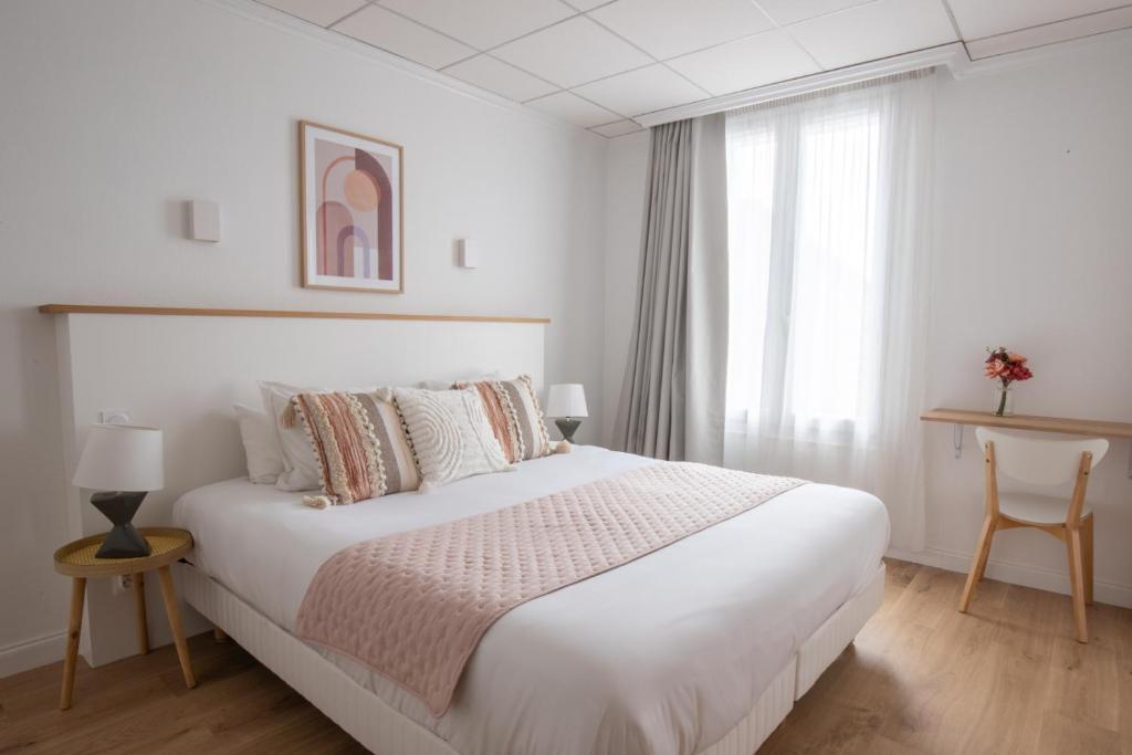 a white bedroom with a large bed and a window at Hôtel Porte Mars Reims Gare Centre Arena in Reims