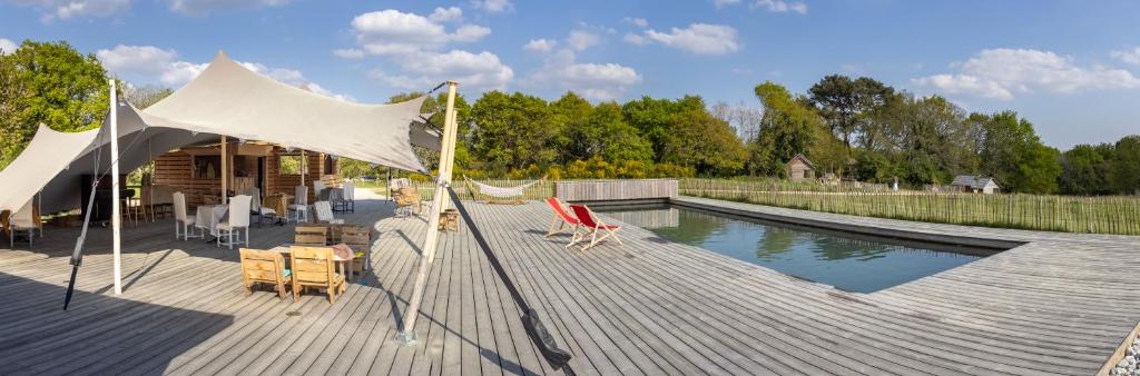 a deck with a pool with a tent and chairs at Dihan Evasion in Ploemel