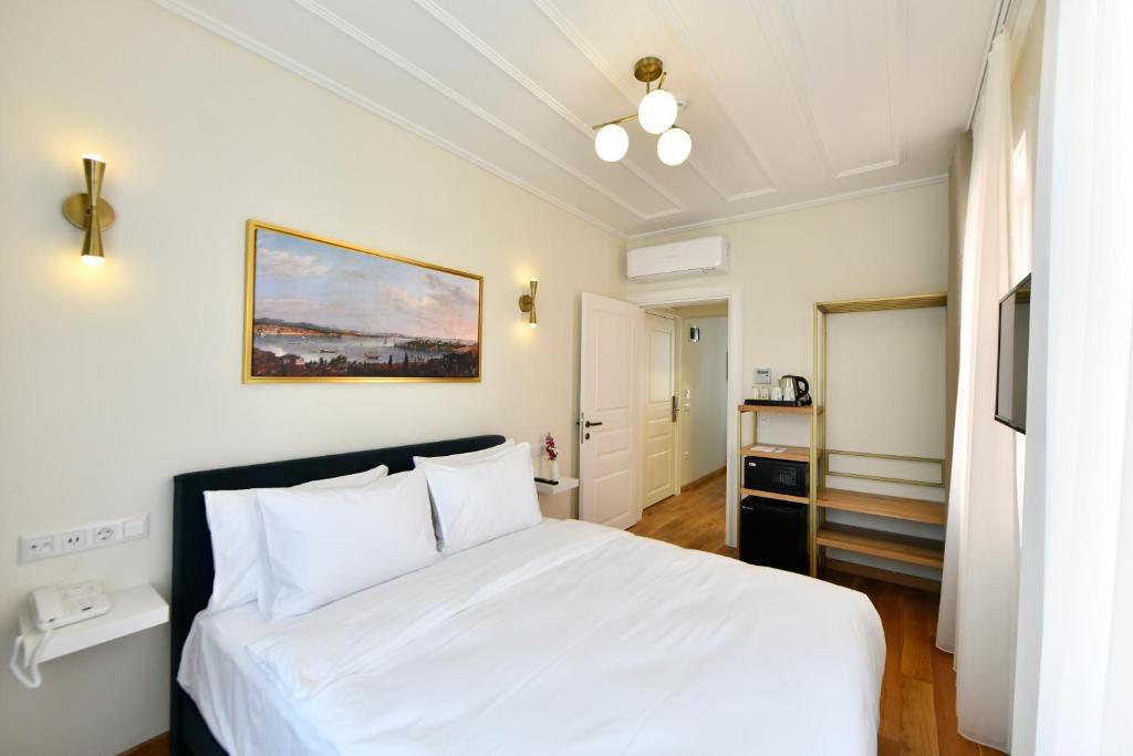 a bedroom with a white bed and a painting on the wall at Agras Hotel in Istanbul