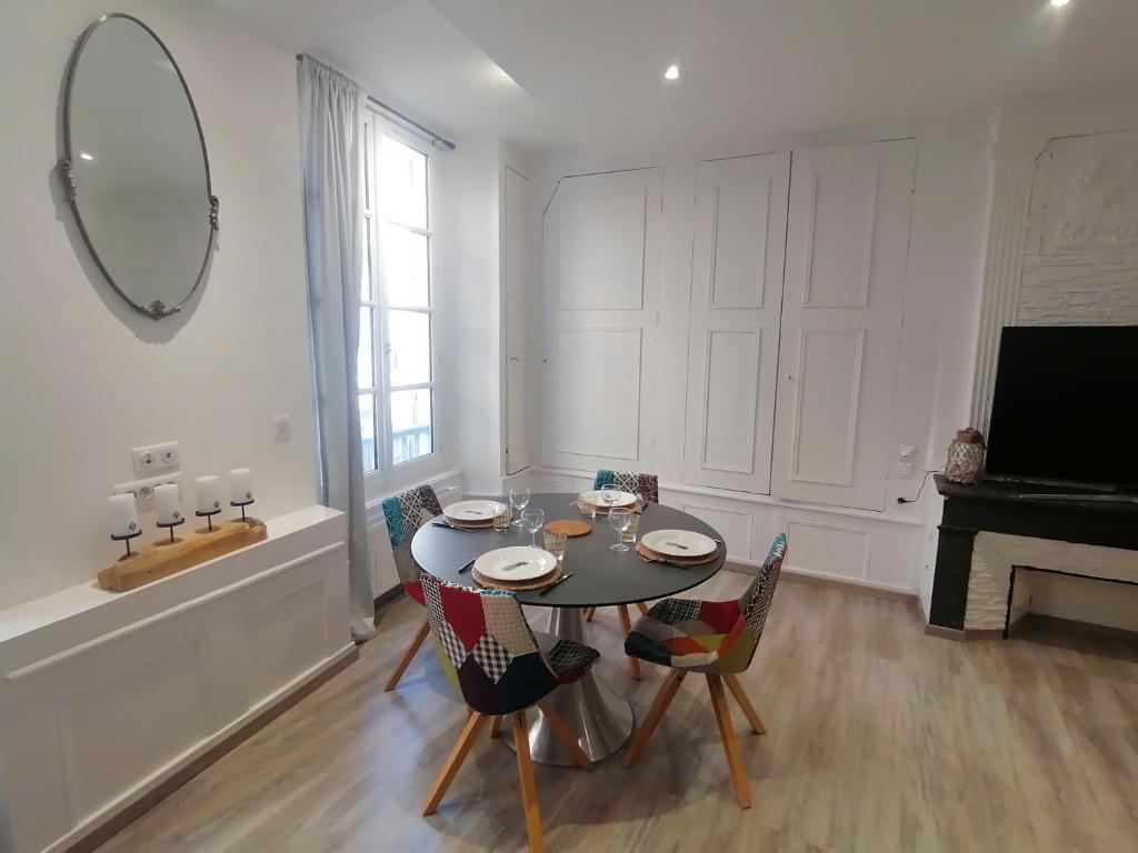 - une salle à manger avec une table, des chaises et un miroir dans l'établissement Appartement F2 dans le centre historique, au Puy-en-Velay