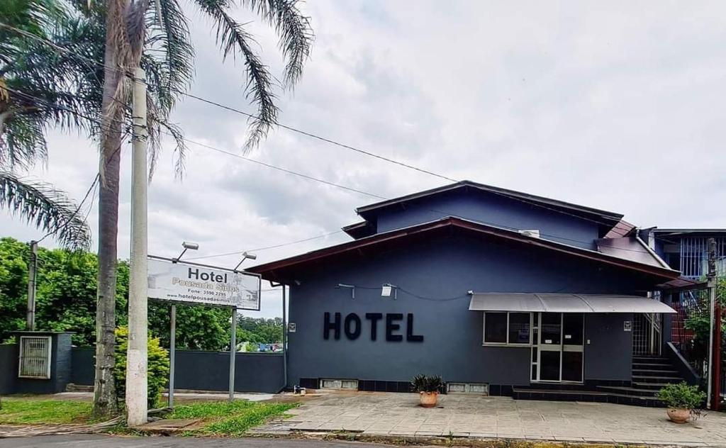 a hotel with a blue building and a palm tree at Hotel Pousada Sinos in São Leopoldo