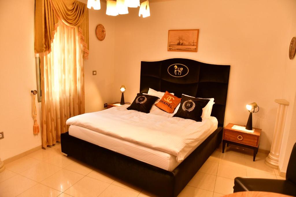 a bedroom with a large bed with orange and black pillows at The German House in ‘Akko