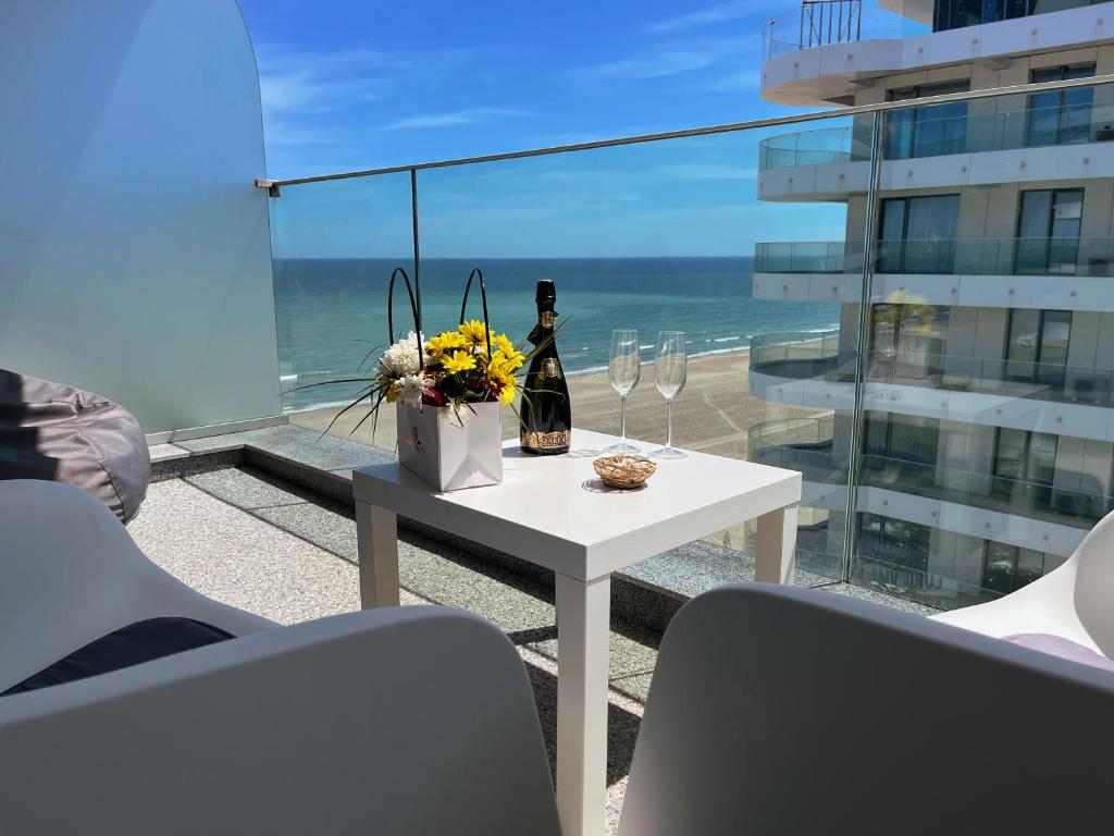 a table with a bottle of wine and flowers on a balcony at Studio 147 Mamaia Nord in Mamaia
