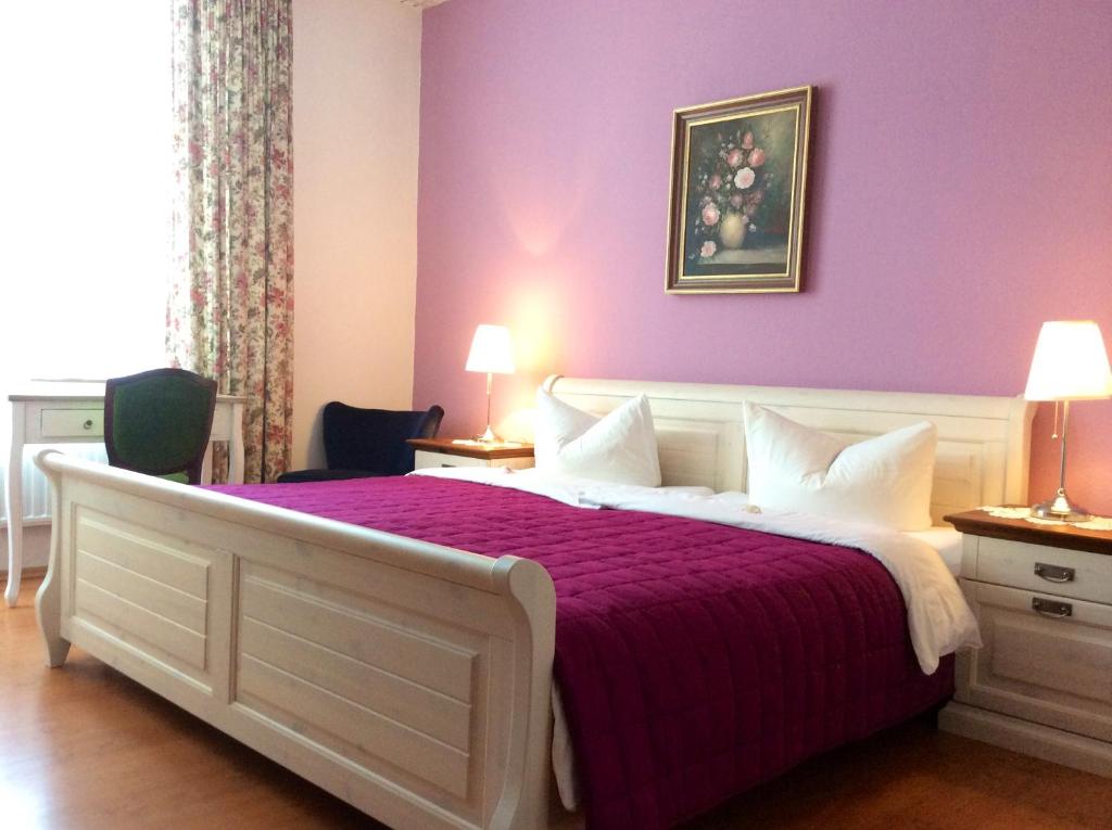 a bedroom with a bed with a purple wall at Hotel Hölscher in Solingen