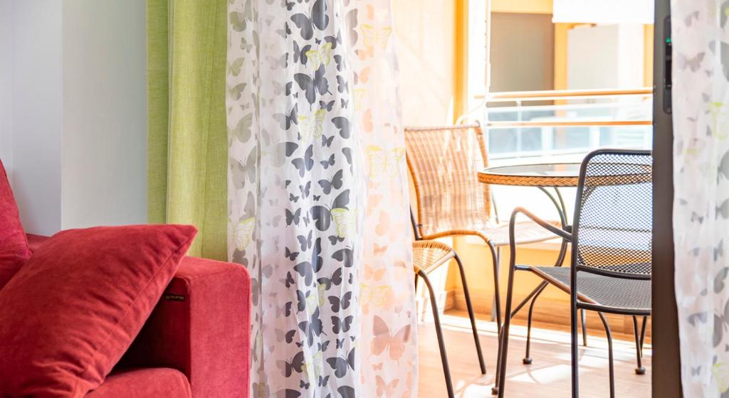 a living room with a red couch and a table and chairs at Parrot’s House in Lloret de Mar