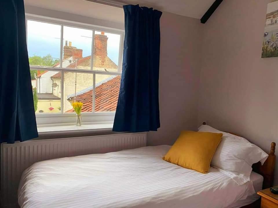 um quarto com uma cama e uma janela com cortinas azuis em The Bell Inn em Norwich