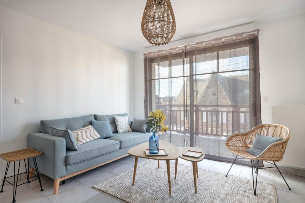 un salon avec un canapé bleu et une table dans l'établissement À 50m de la plage, appartement vue mer 6 pers, à Pléneuf-Val-André