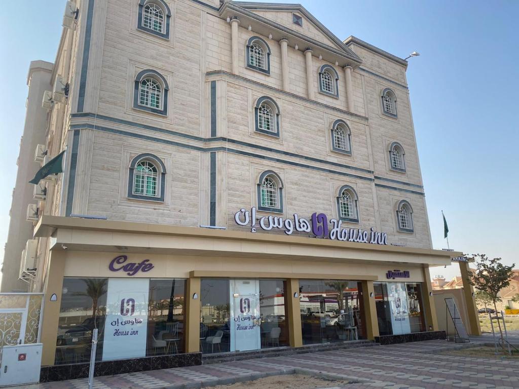 una tienda frente a un edificio con un cartel. en هاوس إن House Inn, en Najrán