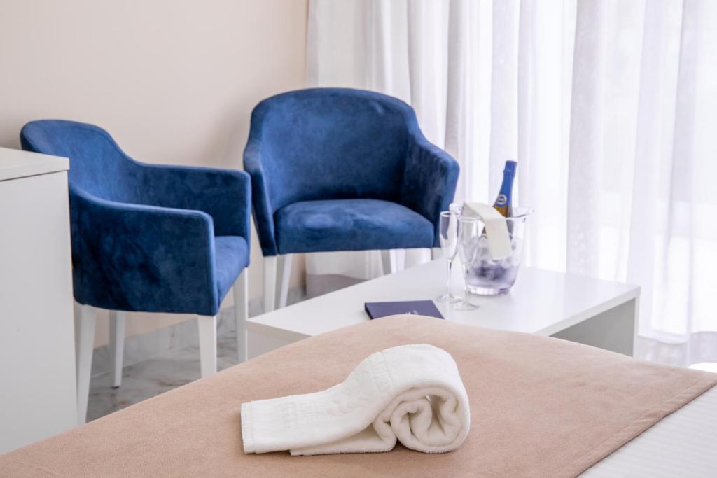 a room with blue chairs and a towel on a bed at Lagos Atlantic Hotel in Lagos