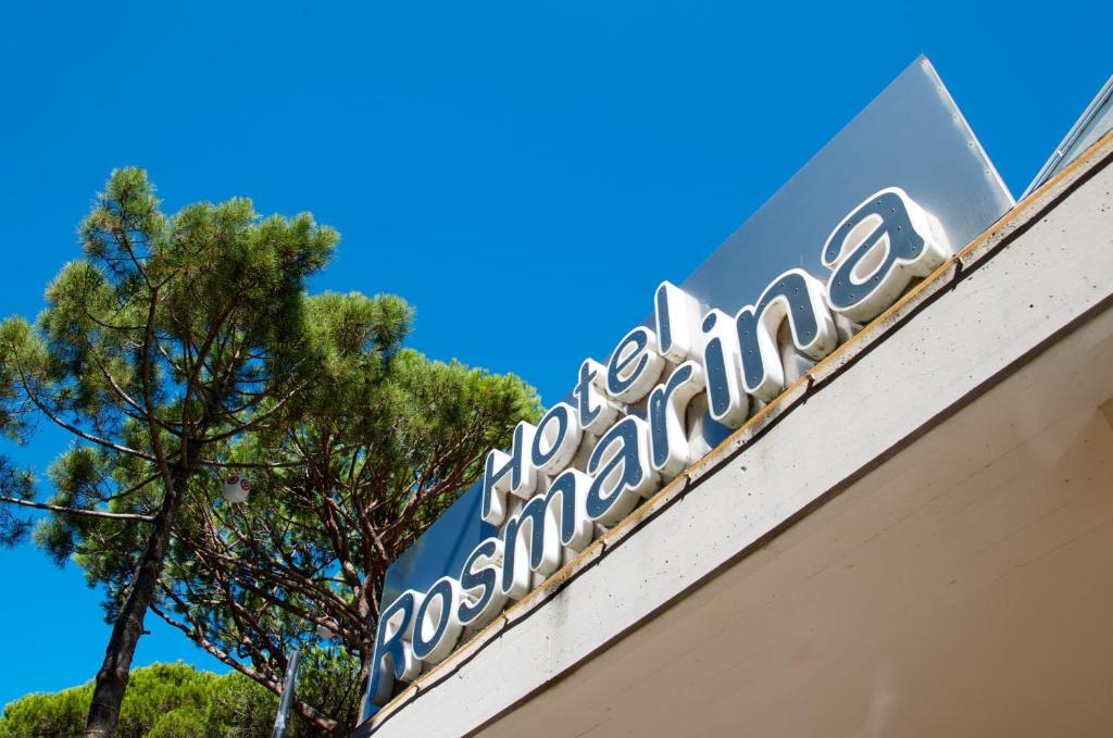 a sign on top of a building with a tree at Hotel Rosmarina in Marina di Grosseto