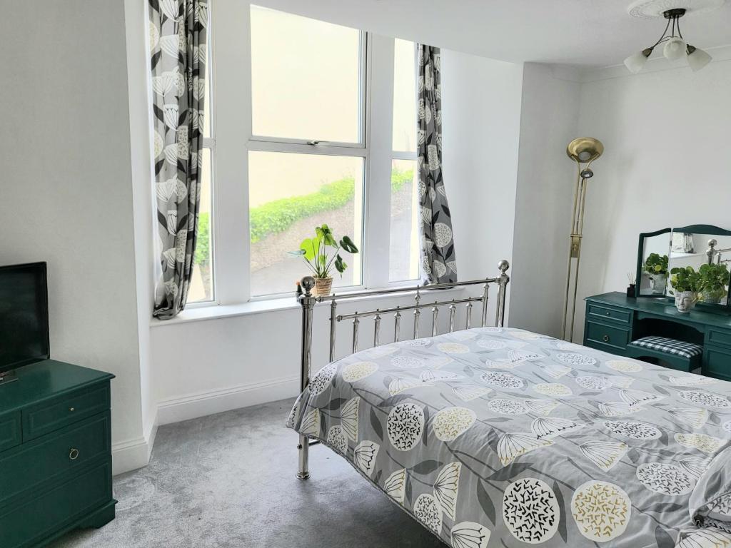 um quarto com uma cama e uma janela em Loveliest Homes Torquay - 3 bed, 2 bathroom, balcony, parking em Torquay