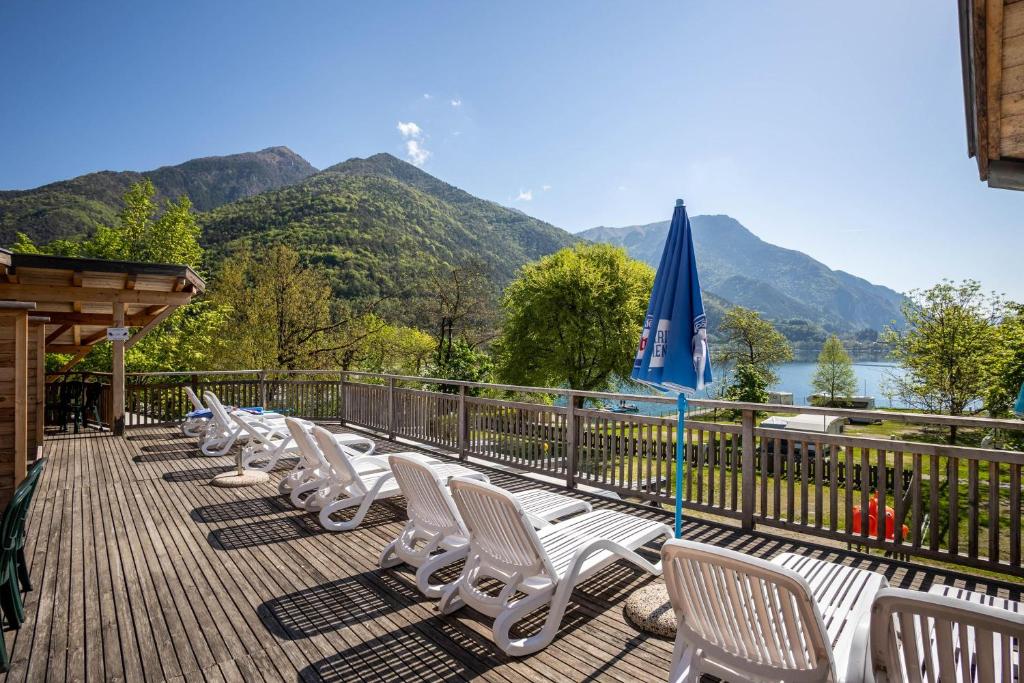 - une rangée de chaises longues blanches sur une terrasse avec des montagnes dans l'établissement Camping Al Lago Appartamento 4, à Pieve Di Ledro