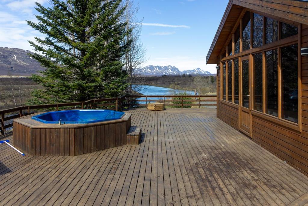 a hot tub on a deck next to a building at Gorgeous Riverside Lodge in the South of Iceland in Reykholt