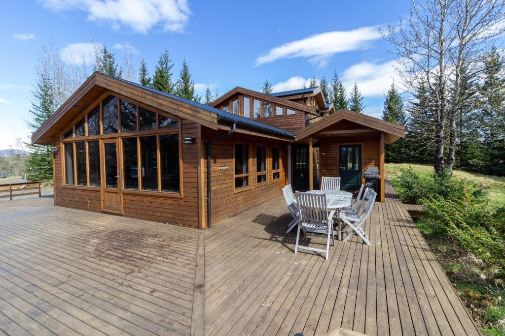 una cabina con terrazza, tavolo e sedie di Gorgeous Riverside Lodge in the South of Iceland a Reykholt