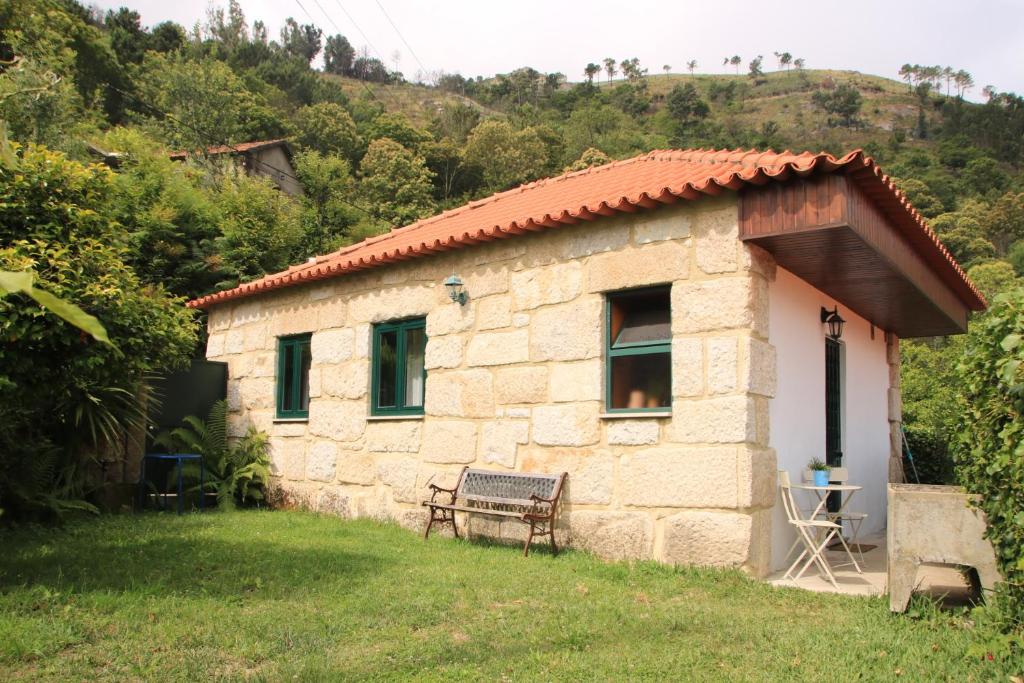 una piccola casa in pietra con una panchina accanto di Douro Senses - Village House a Cinfães