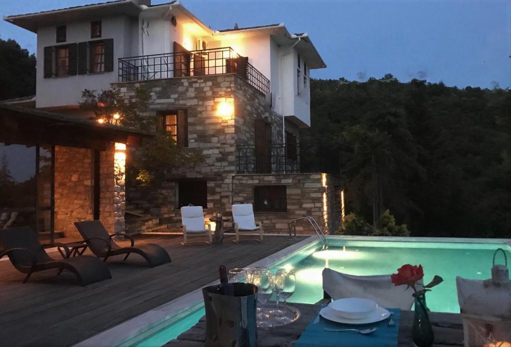 a villa with a swimming pool in front of a house at Art Luxury Resort Villa in Áyios Vlásios