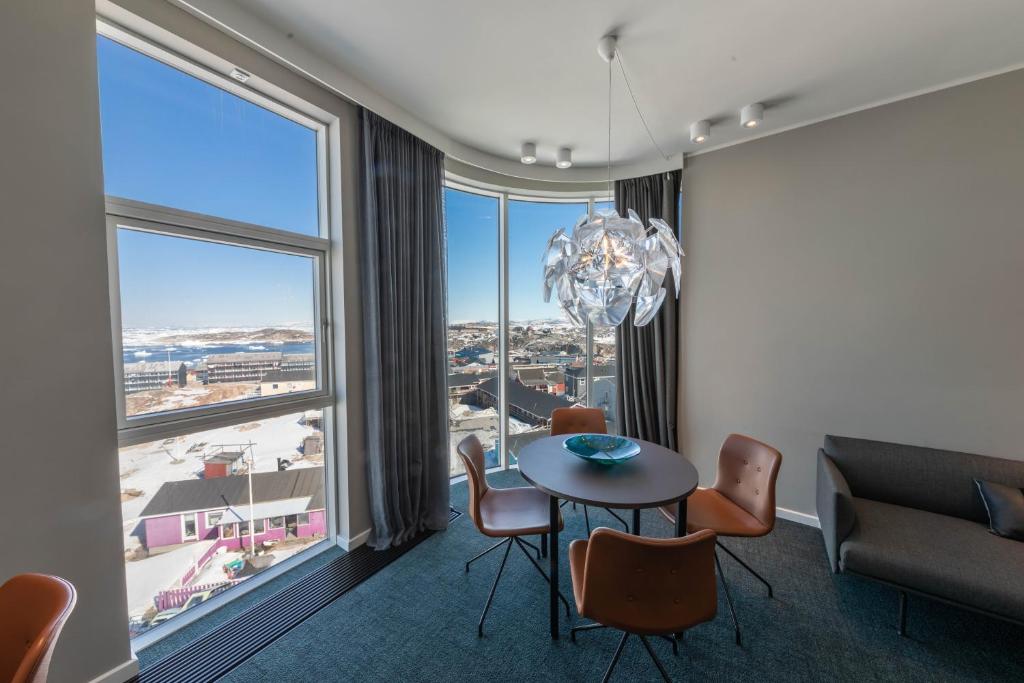 a dining room with a table and chairs and a large window at Best Western Plus Hotel Ilulissat in Ilulissat