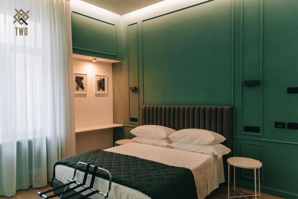 ein Schlafzimmer mit grünen Wänden und einem Bett mit weißen Kissen in der Unterkunft Four Pompei in Pompei