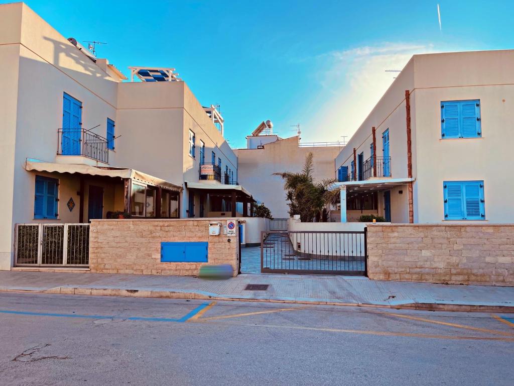 grupa budynków z niebieskimi oknami na ulicy w obiekcie appartamento residence via giardini Acquamarina w mieście San Vito lo Capo