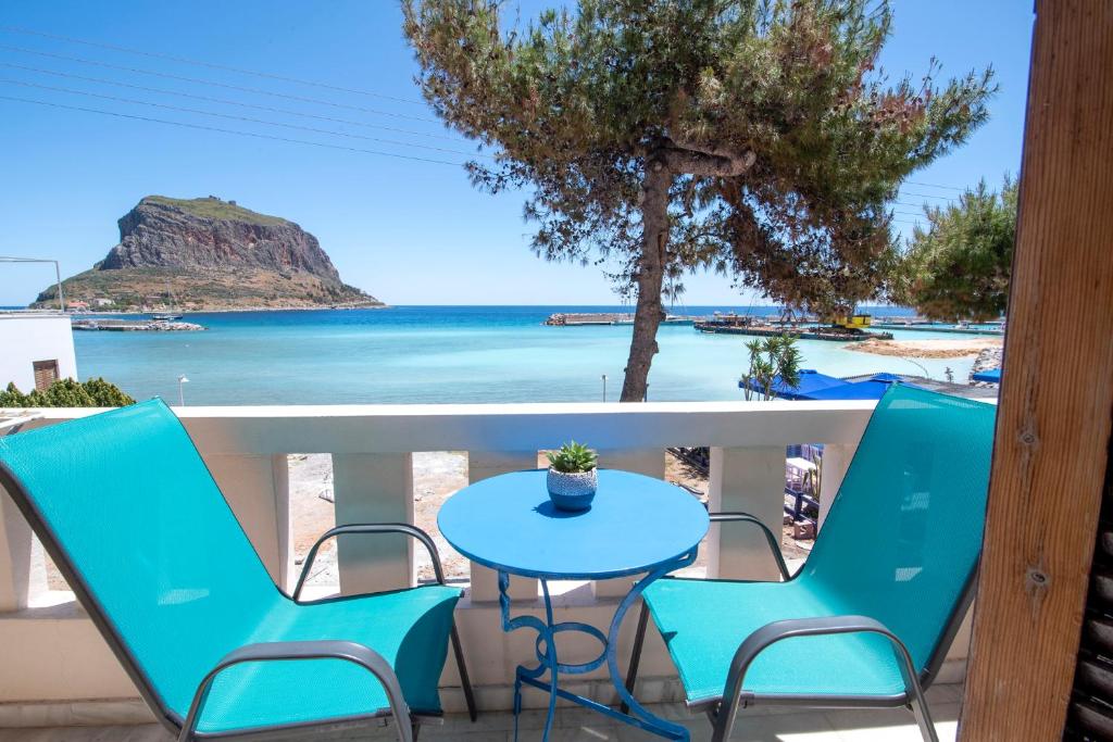 een tafel en stoelen op een balkon met uitzicht op het strand bij Aeolos Guesthouse in Monemvasia