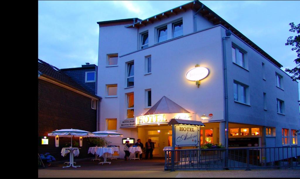 ein großes weißes Gebäude mit Menschen, die draußen stehen in der Unterkunft Hotel Abalone in Remscheid