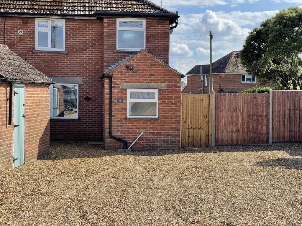 uma casa de tijolos com um portão de madeira e uma cerca em Coastal getaway in Heacham em Heacham