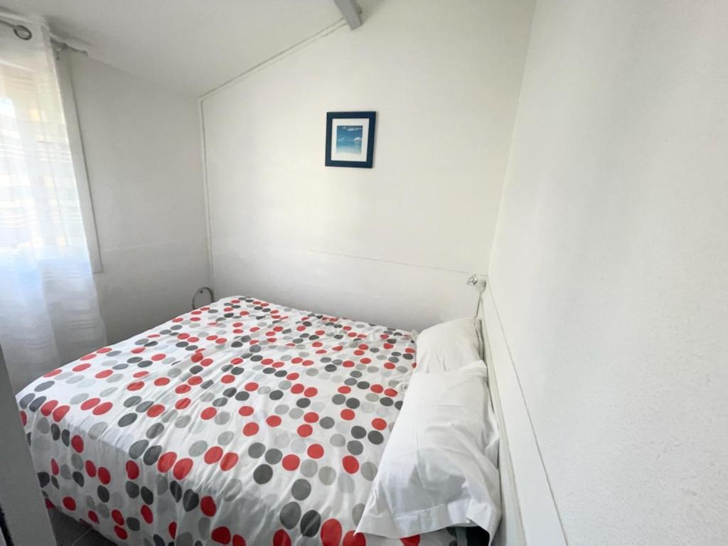 ein Schlafzimmer mit einem Bett mit einer Polka-Dot-Tagesdecke in der Unterkunft Bel appartement à 300 mètres de la plage +parking in Valras-Plage