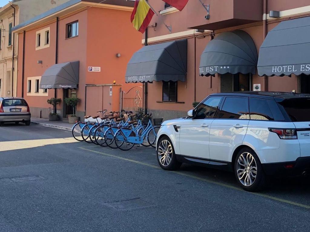 un SUV bianco parcheggiato di fronte a una fila di biciclette di Hotel Est Piombino a Piombino