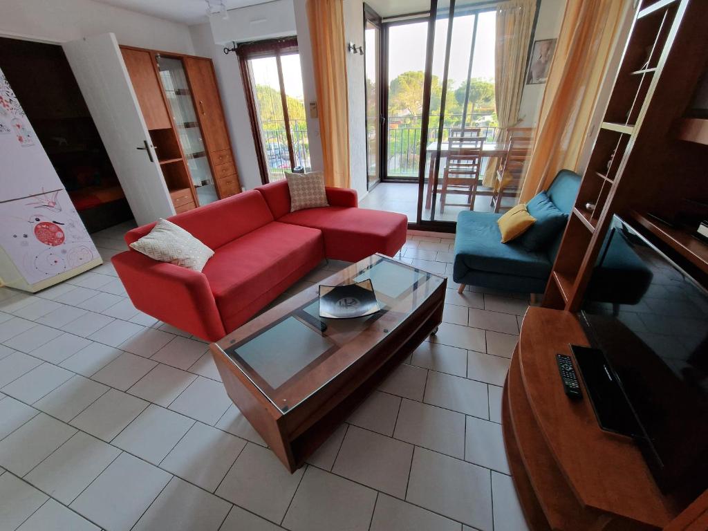 - un salon avec un canapé rouge et une table dans l'établissement Résidence Les Mers du Sud Port Argelès, à Argelès-sur-Mer