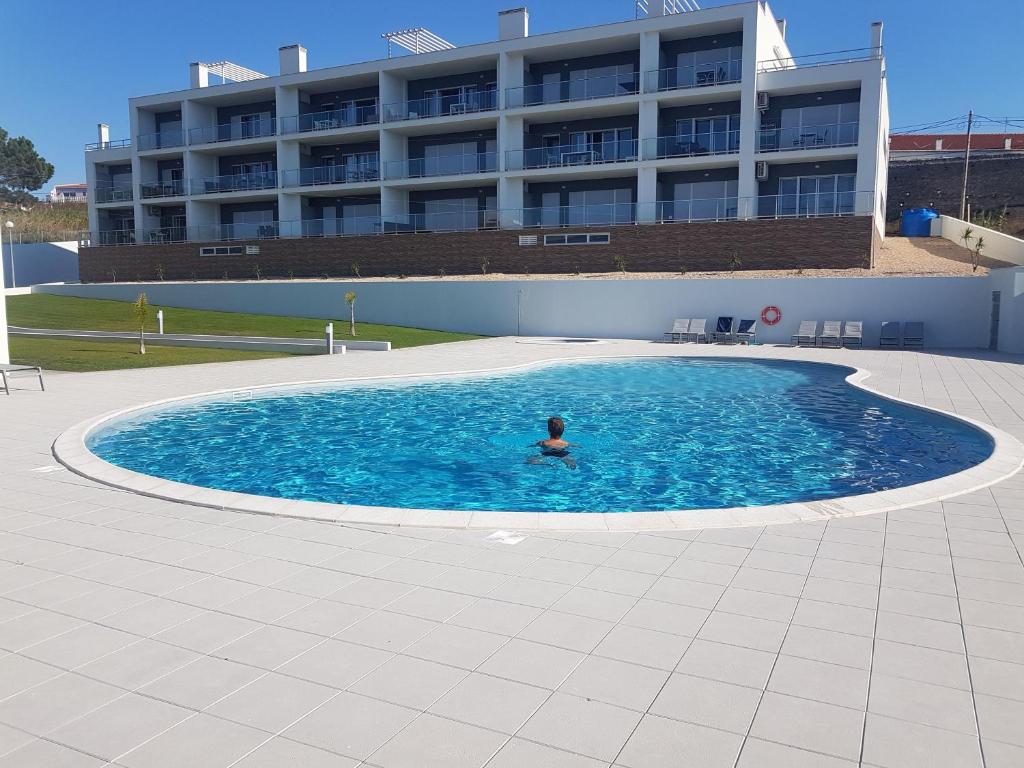 une personne dans une piscine avec un bâtiment en arrière-plan dans l'établissement Sonho do Mar Ap., à Nazaré