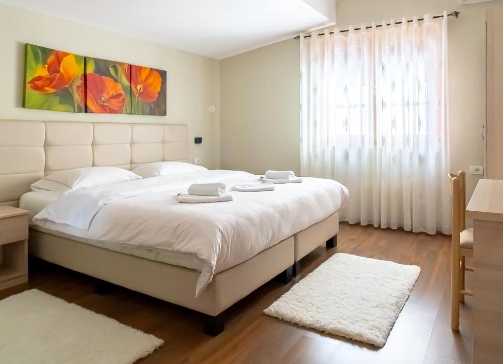 a bedroom with a large white bed and a window at Garden Boutique B&B in Tirana
