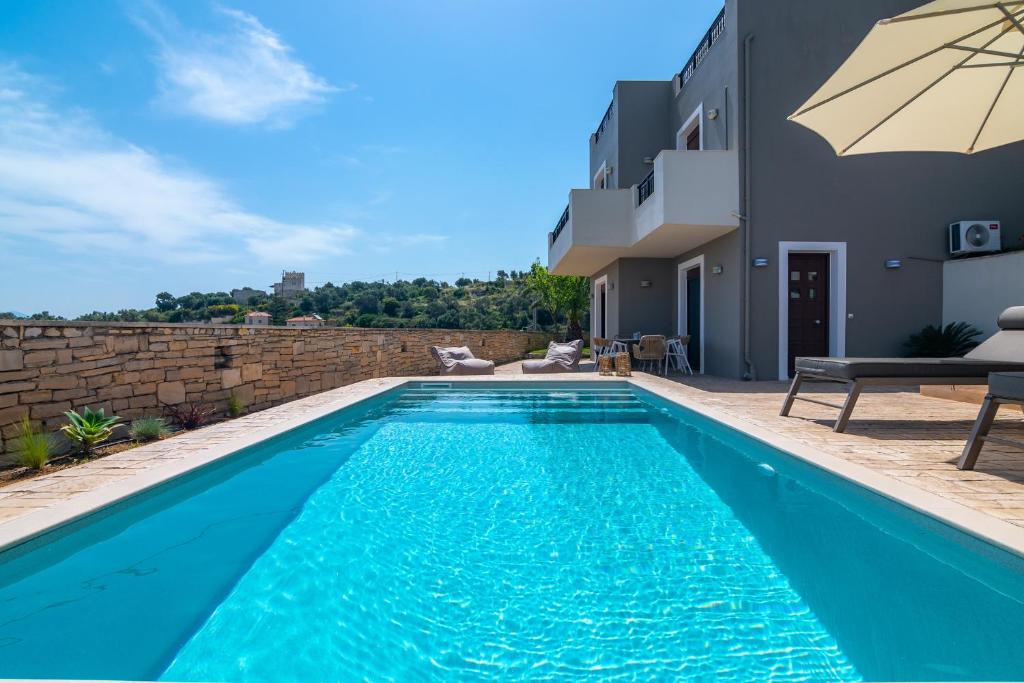 una piscina con sombrilla junto a una casa en Villaki en Maroulás