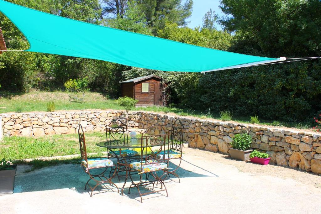 einen Tisch und Stühle unter einem blauen Schirm in der Unterkunft Gite La clef du Sud in Salernes