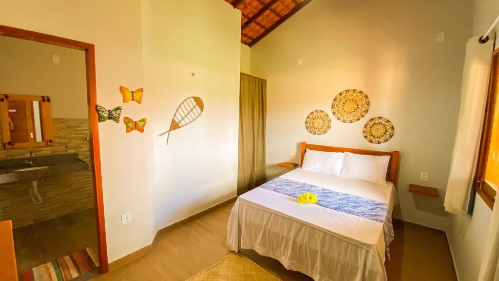 - une chambre avec un lit orné d'une fleur jaune dans l'établissement Maracujá Village, à Ponta do Anel