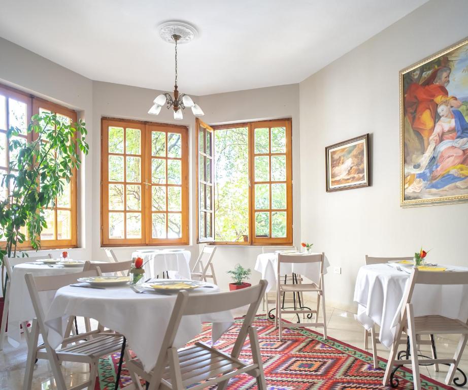 a dining room with white tables and chairs and windows at Garden Boutique B&B in Tirana