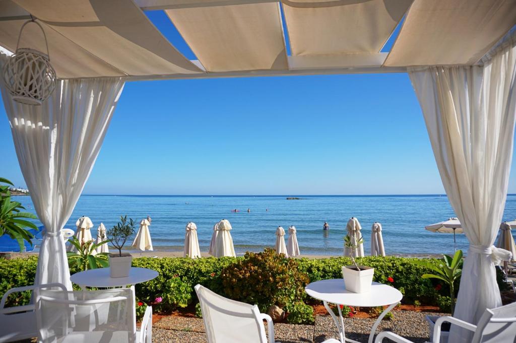 vista para a praia a partir de um restaurante com mesas e cadeiras em Talgo Suites em Stalida