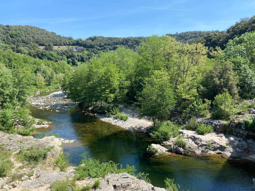 uma vista para um rio com árvores e rochas em La Petite Caserne - Gite 4 étoiles - em Pont-de-Labeaume
