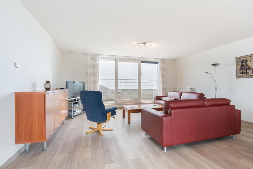 ein Wohnzimmer mit einem Sofa und einem Stuhl in der Unterkunft Hello Zeeland - Appartement Port Scaldis 11-112 in Breskens