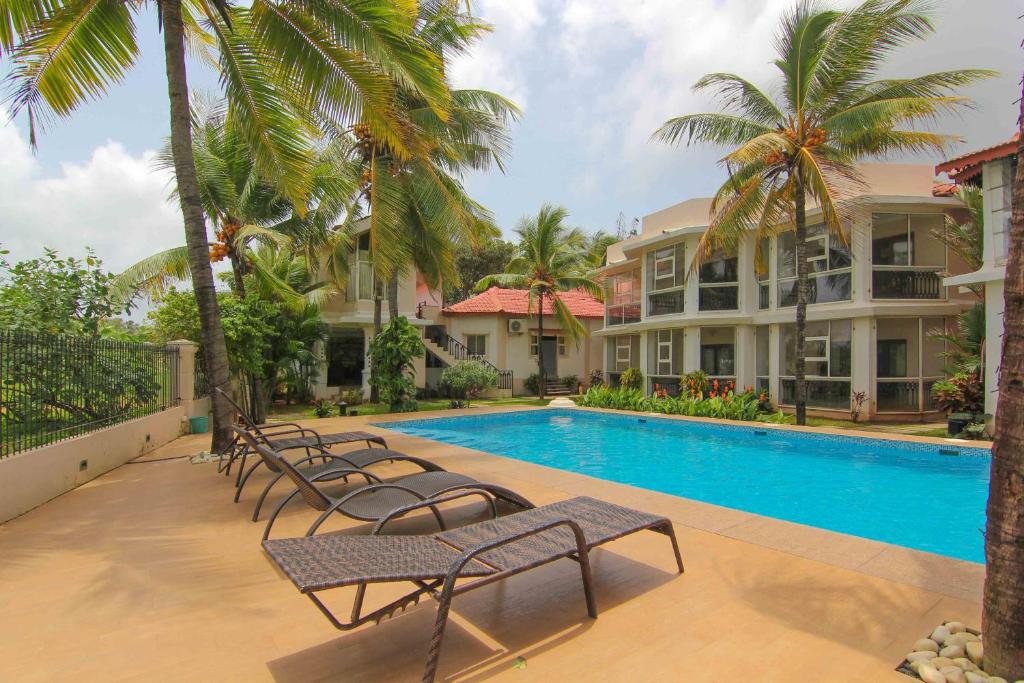 a row of lounge chairs next to a swimming pool at Resort Coqueiral in Candolim