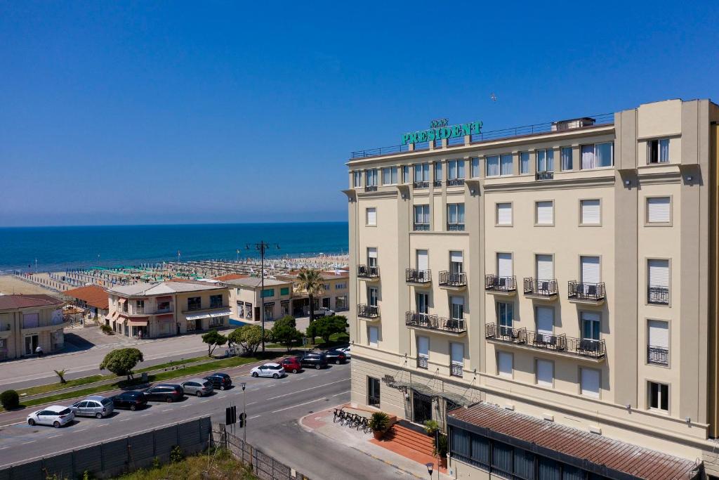 a large white building with the ocean in the background at Hotel President in Viareggio