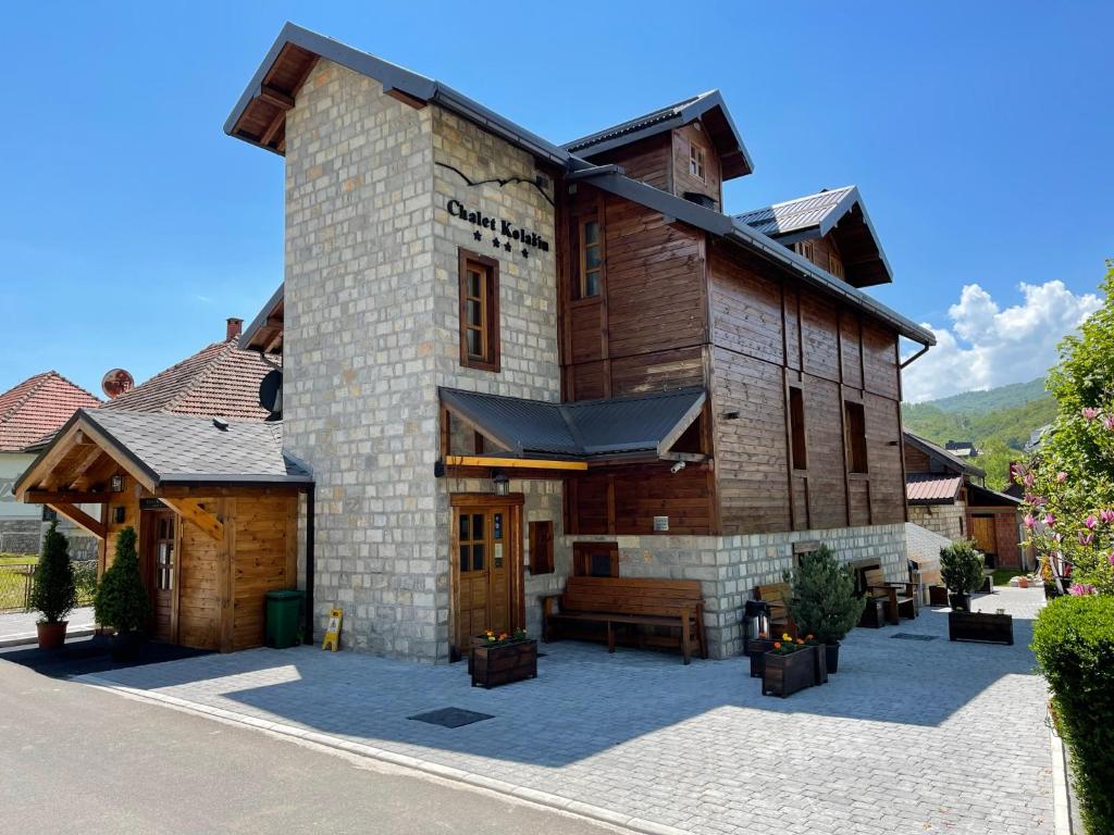 un gran edificio de madera con un banco delante de él en Chalet Kolašin, en Kolašin