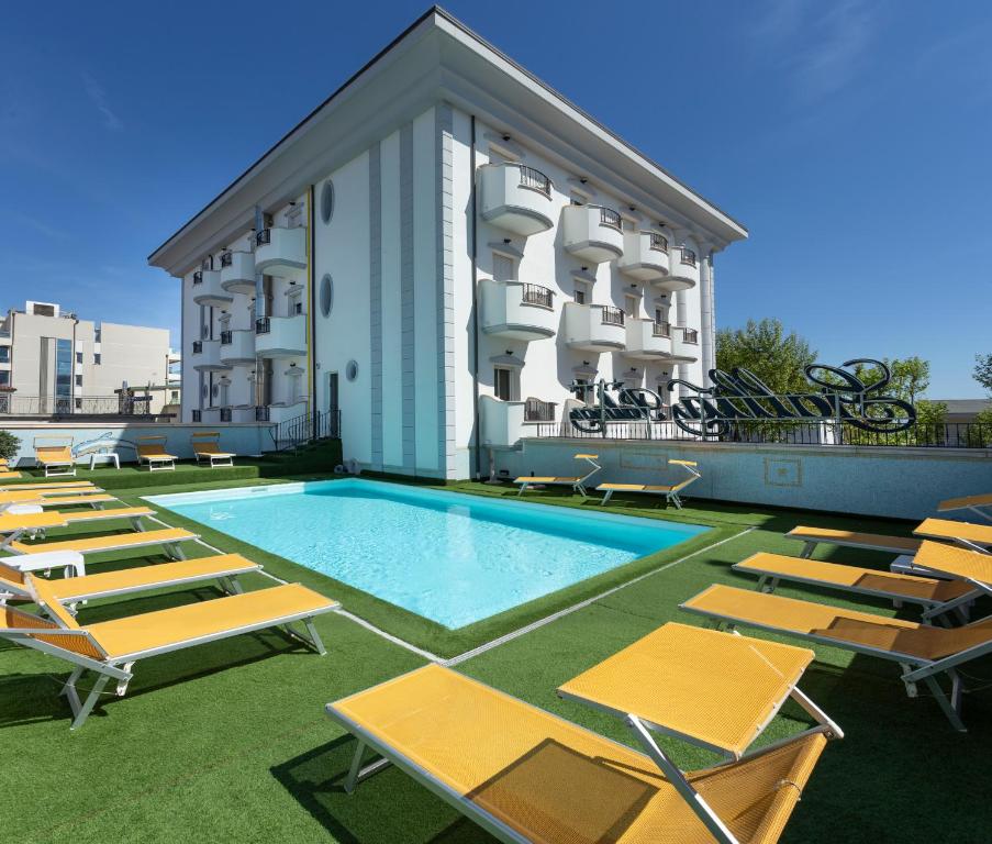 een zwembad met ligstoelen en een gebouw bij Hotel Gallia Palace in Rimini