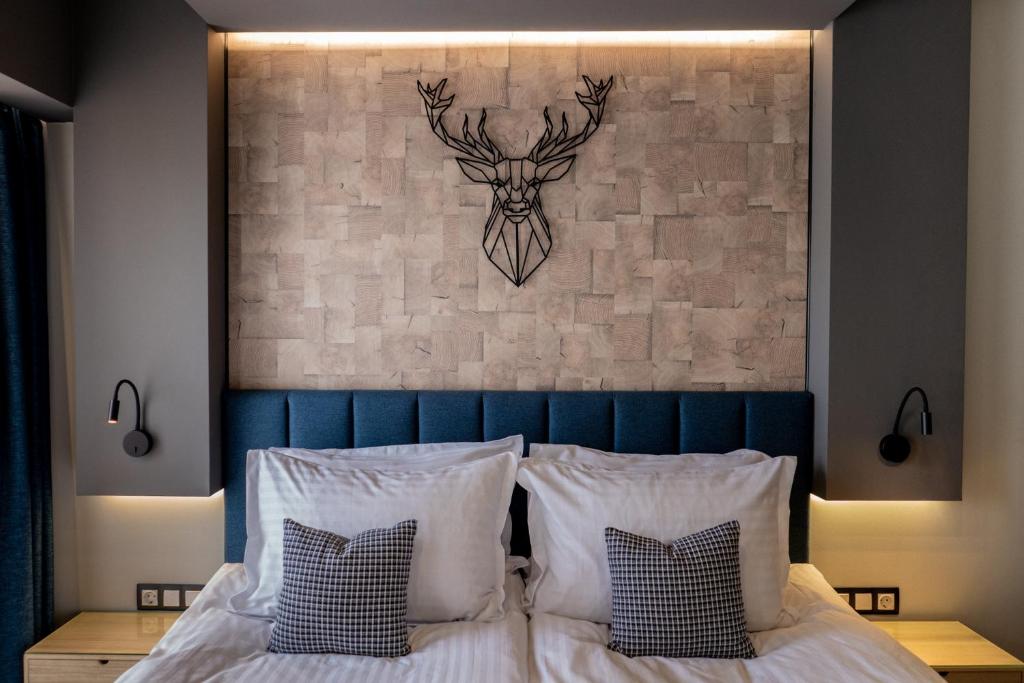1 cama con almohadas blancas y pared con cabeza de ciervo en City Art Luxury Living Free Parking, en Ruse
